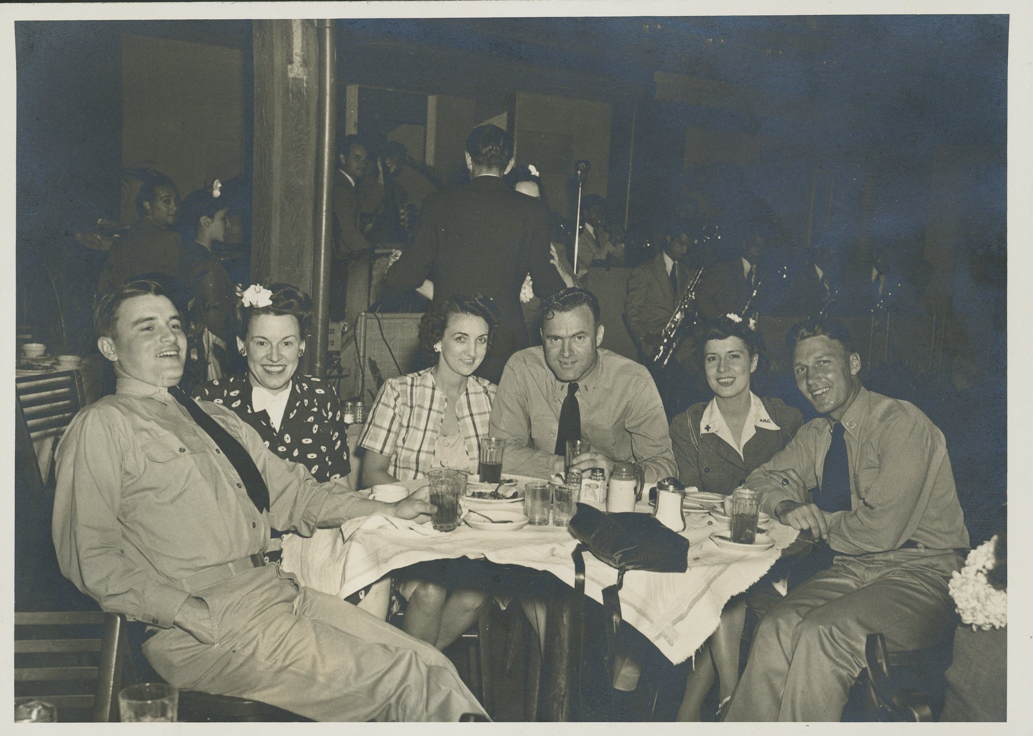 Black and white photograph of three couples of men and women at a restaurant. The men are in military uniforms.